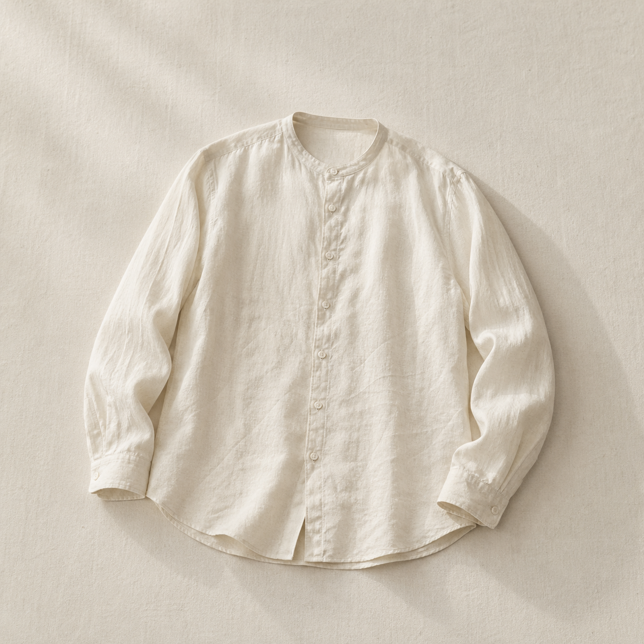 米白亞麻無領襯衫平鋪於亞麻原色背景，自然側光